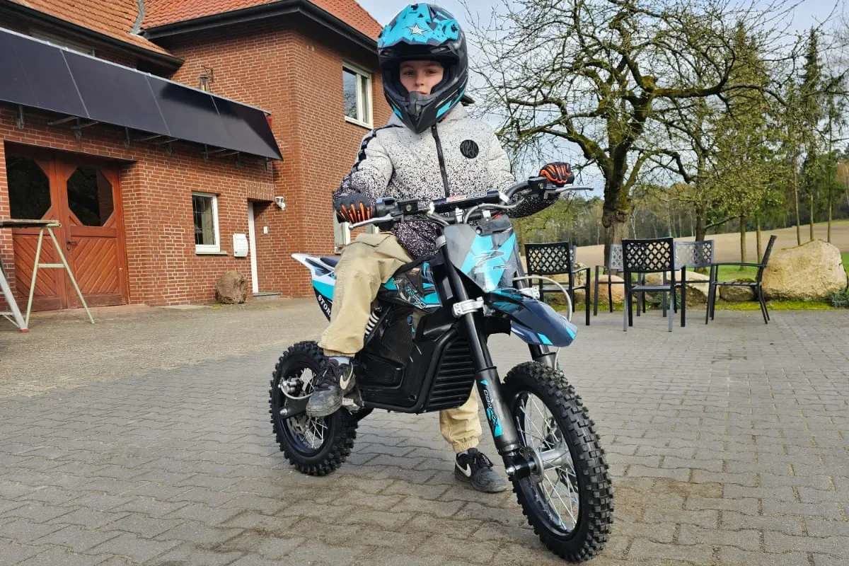 Kind op een blauwe elektrische dirtbike voor een boerderij