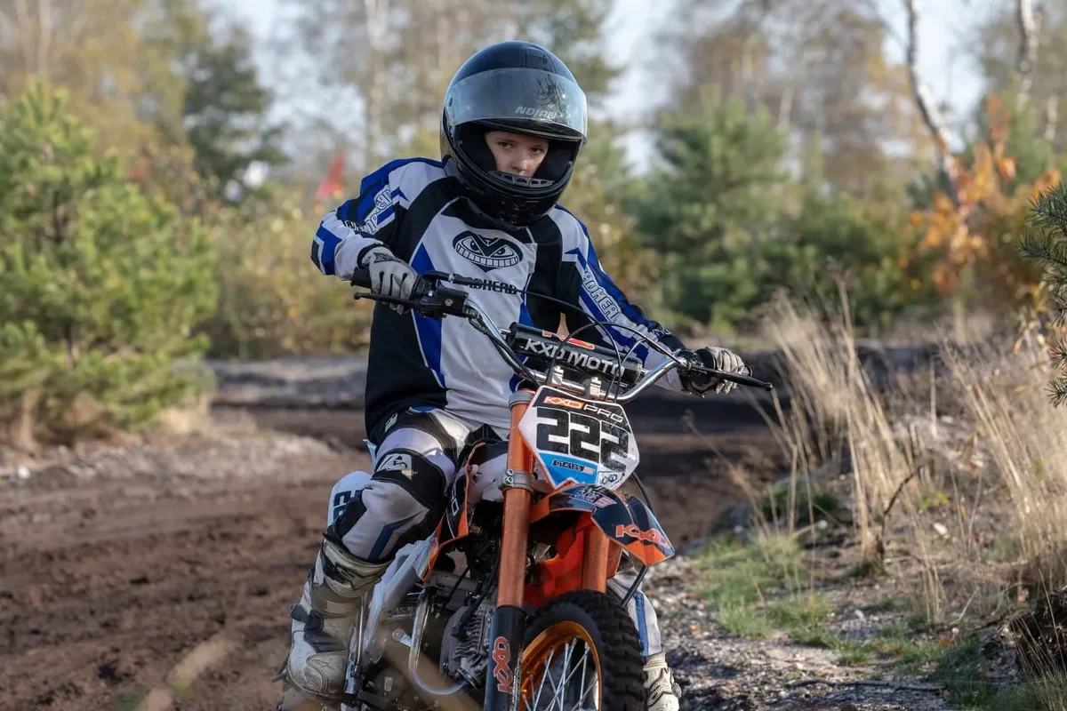 Jonge rijder op een dirtbike op een zandpad