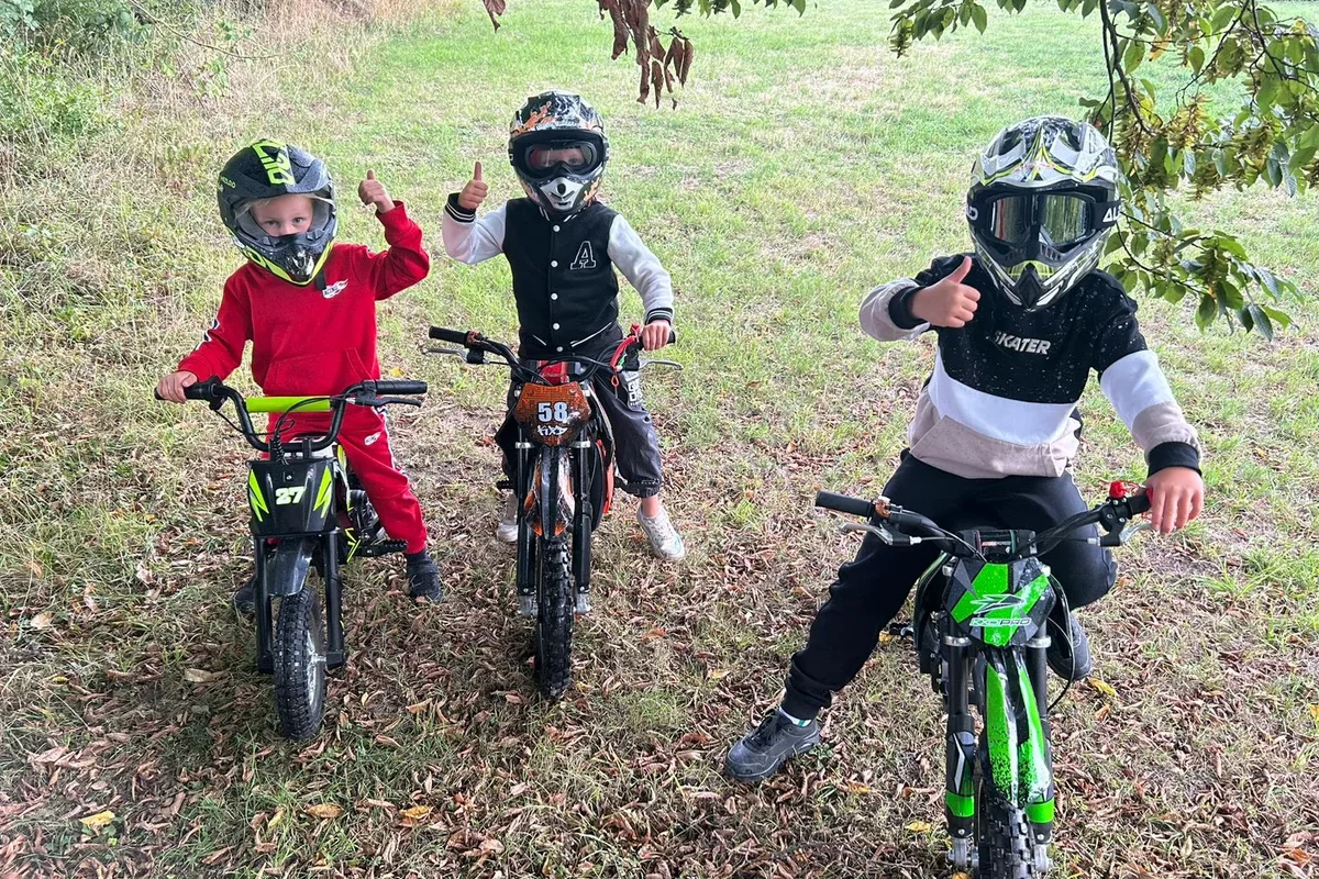 Drie kinderen met hun pitbikes op het gras