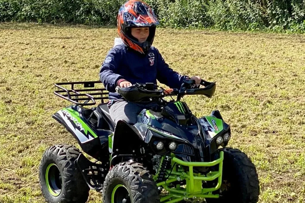 Jongen op een zwarte quad met groene accenten