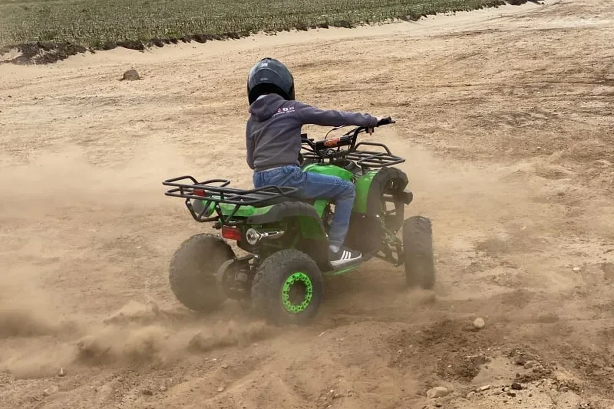 Kind rijdt met een quad door het zand