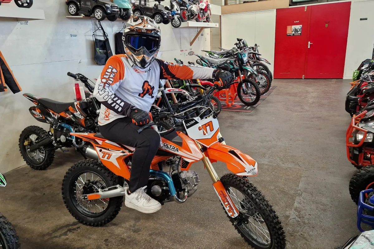 Rijder op een oranje dirtbike in de showroom